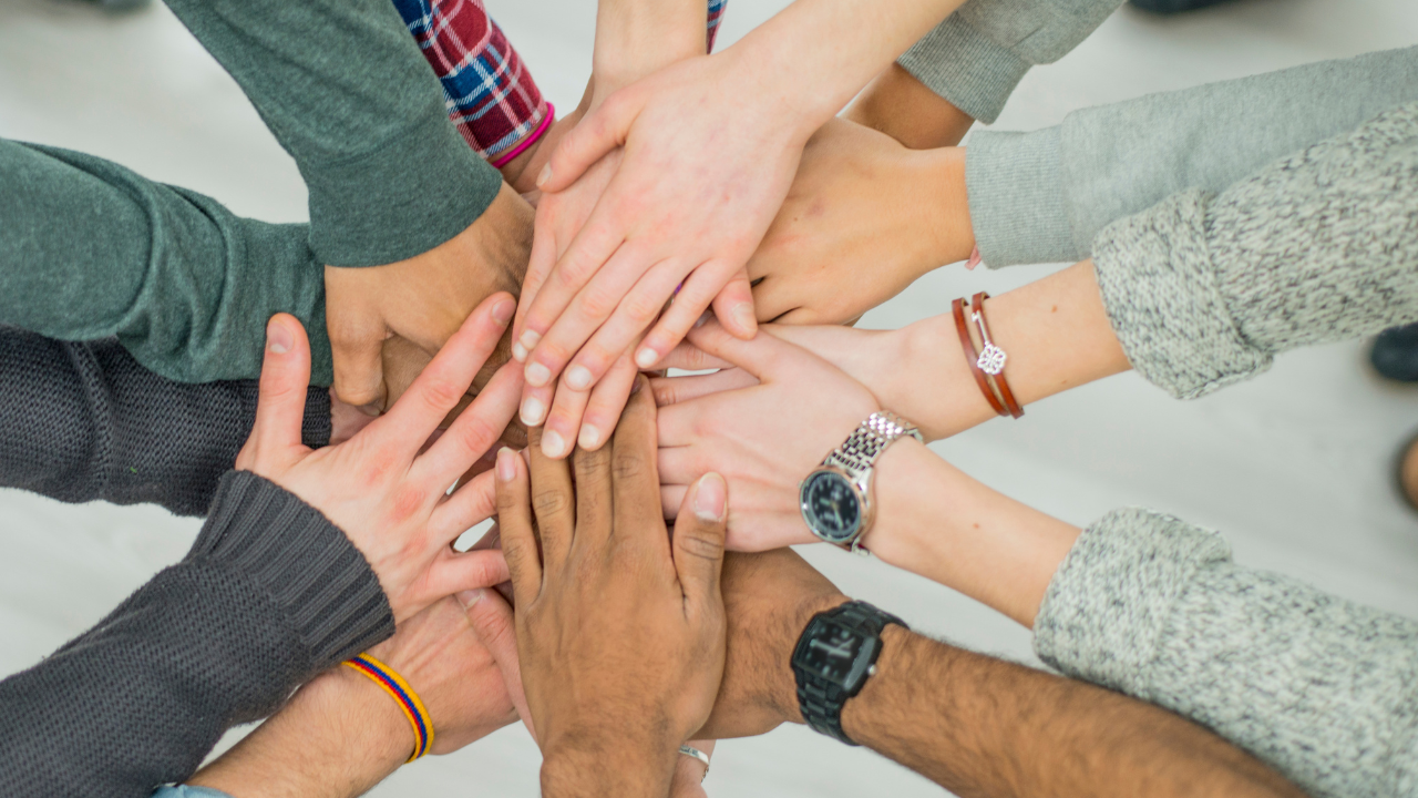 a group of people in a circle with their hands in the middle