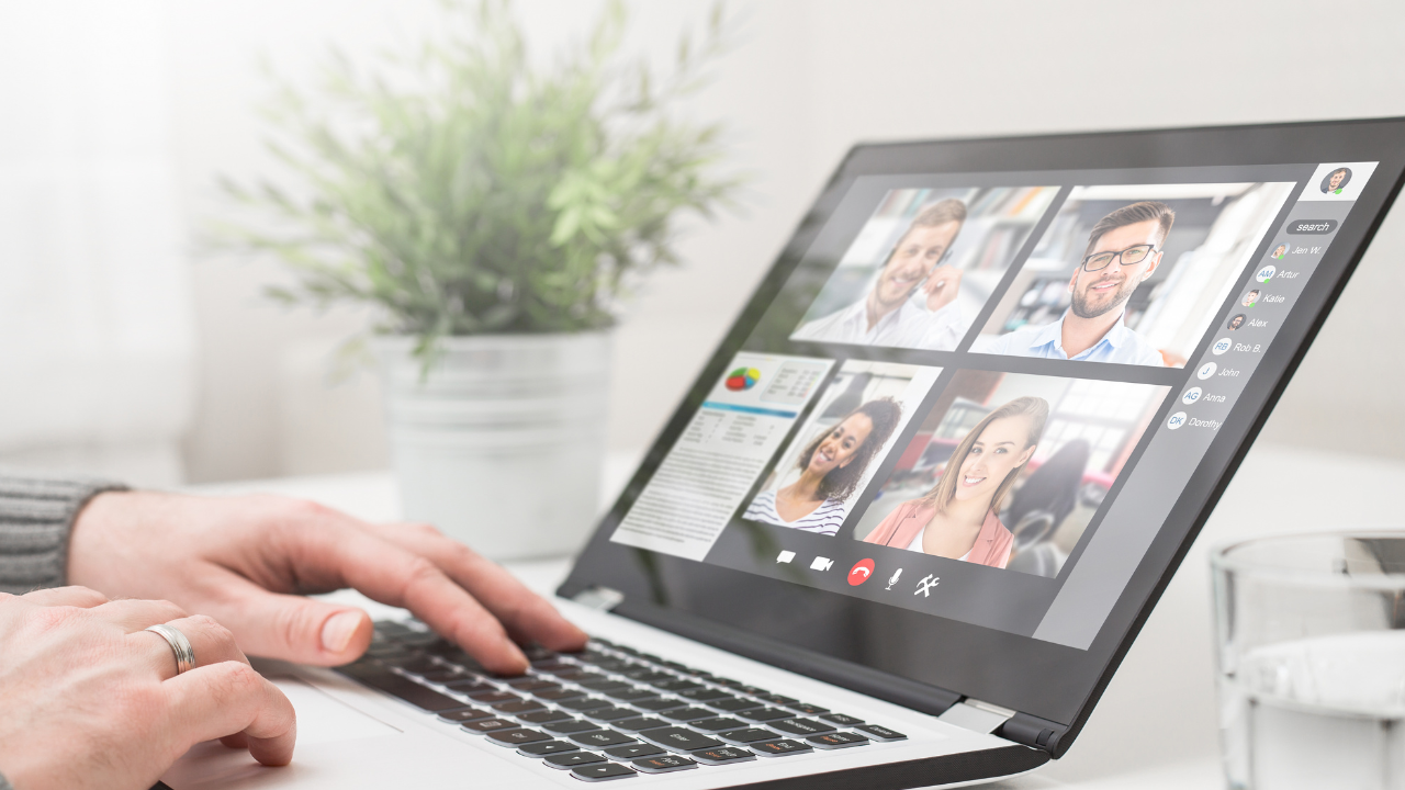 a person is typing on a laptop with several people on the screen